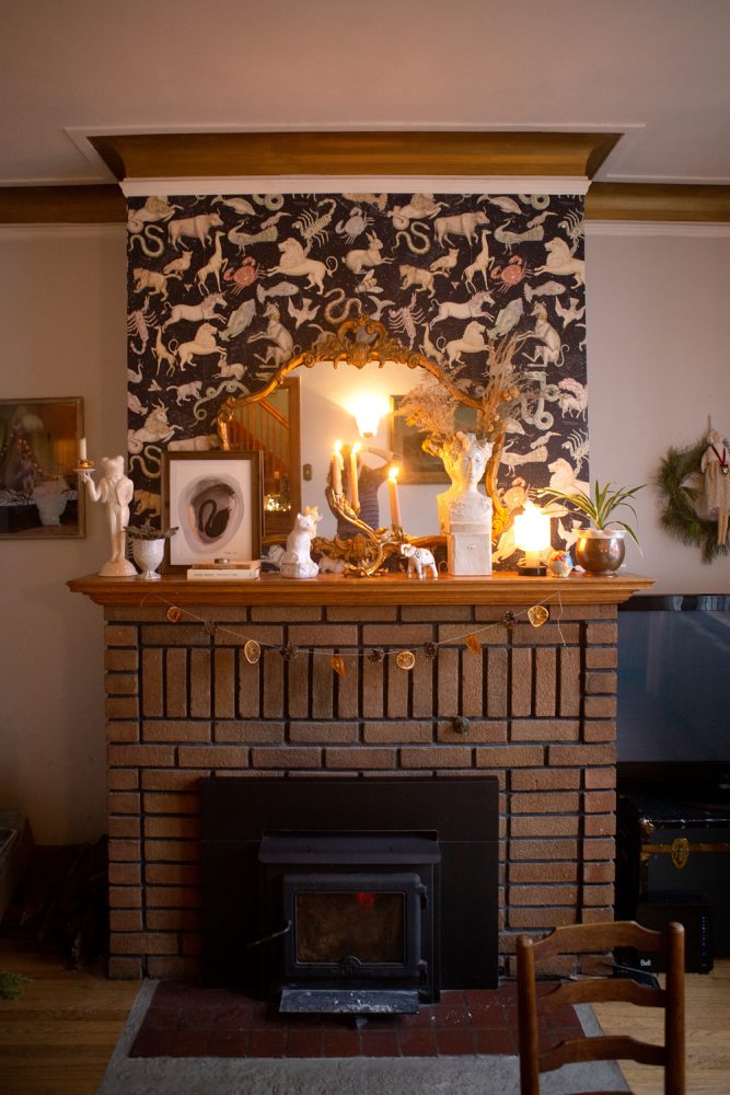 brick fireplace with styled mantel and wallpaper