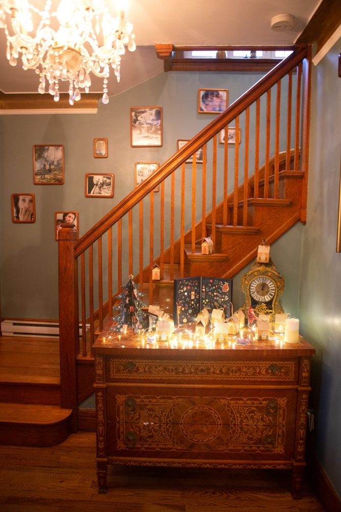 front entryway and staircase with photos on wall and antique clock on cabinet
