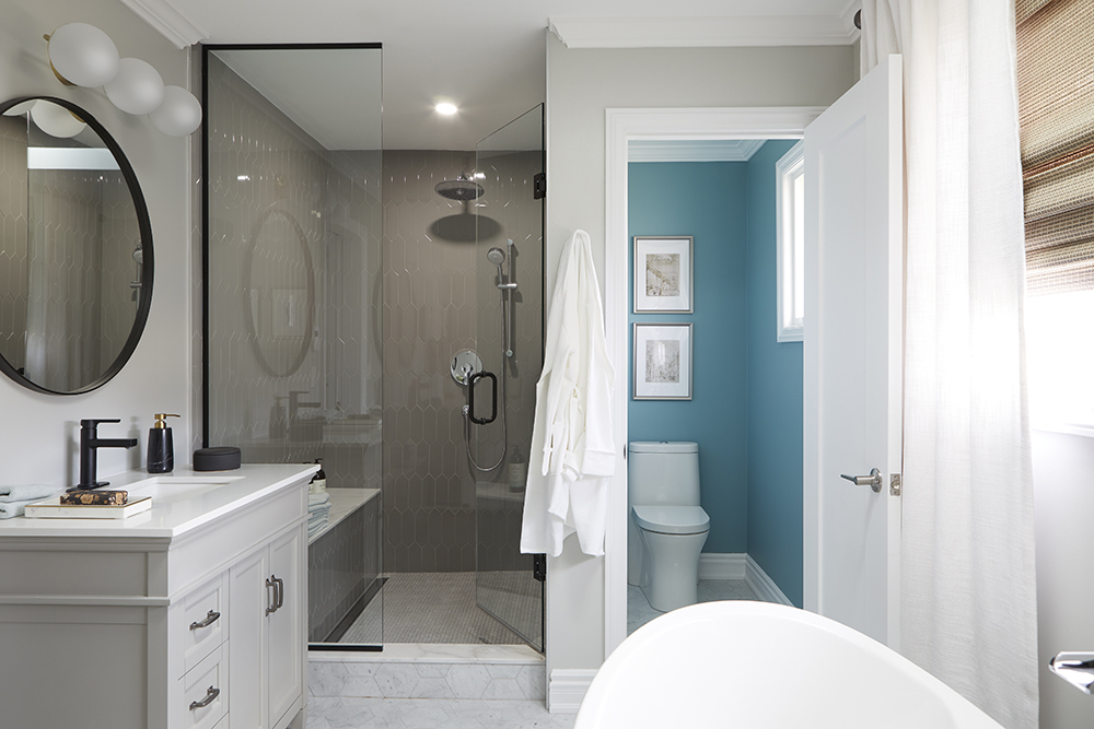 A bathroom with a pale brown shower stall, toilet in a closet space, soaker tub and vanity.