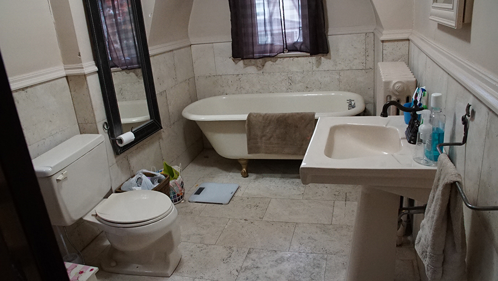 An older bathroom with tiles and a claw foot tub.