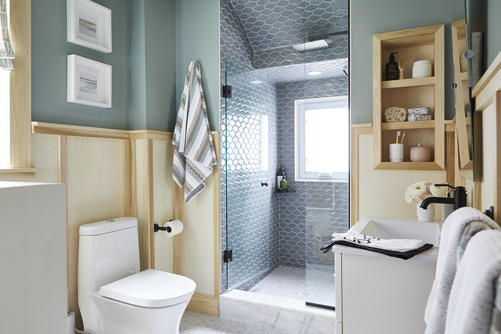 A bathroom with a tall shower stall, a commode and shelving.