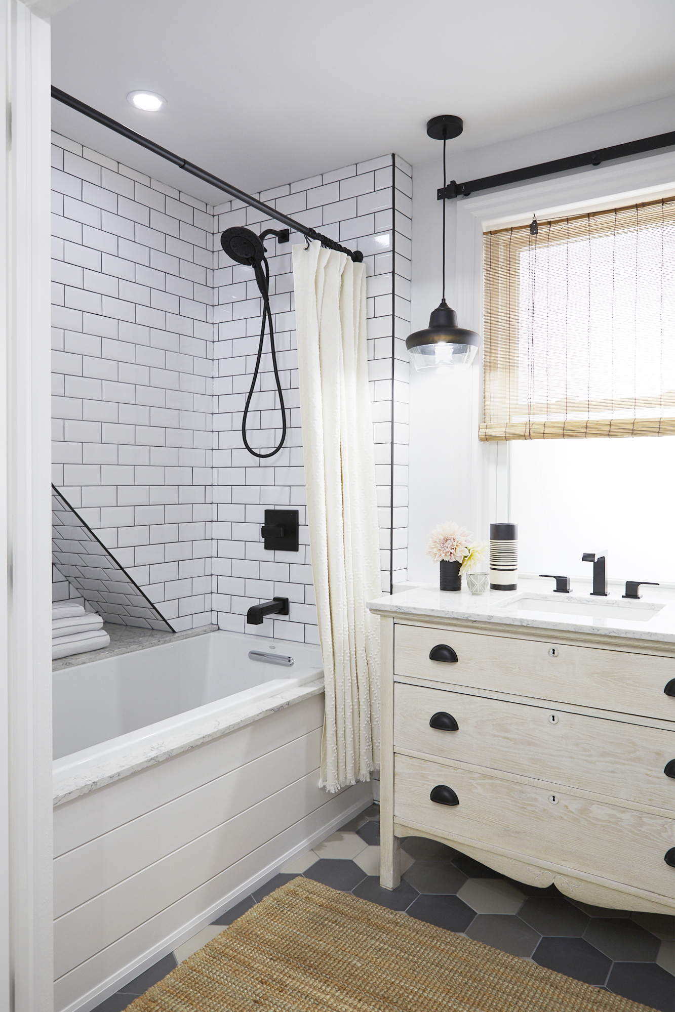 modern white bathroom with white subway tile, wooden vanity and geometric floor tiles