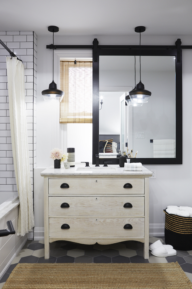 modern white bathroom with sliding mirror, antique vanity and geometric floor tile