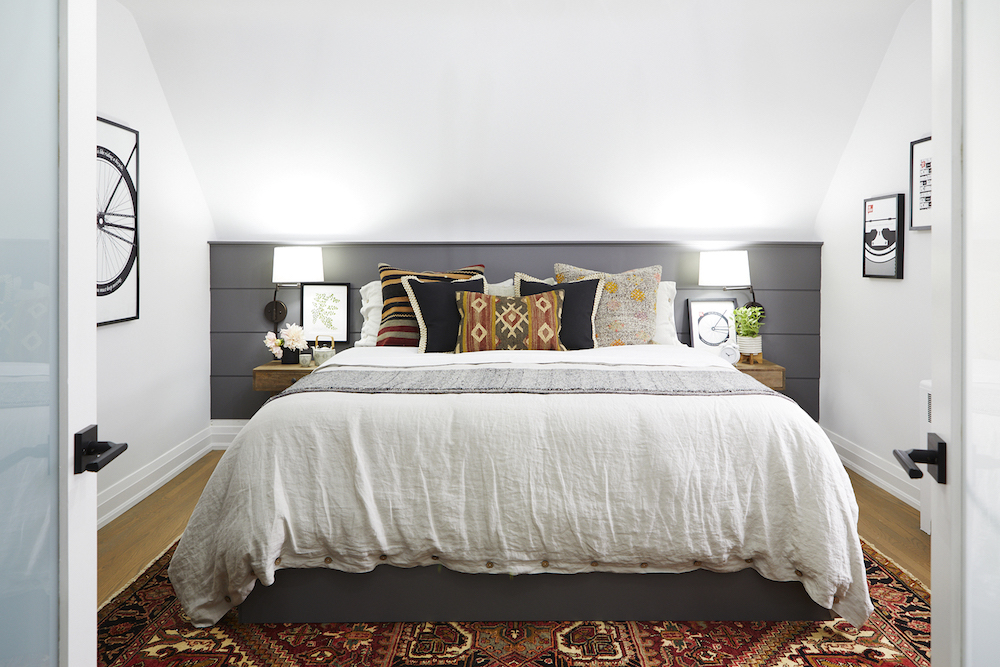 white bedroom with dark grey panels behind white bed