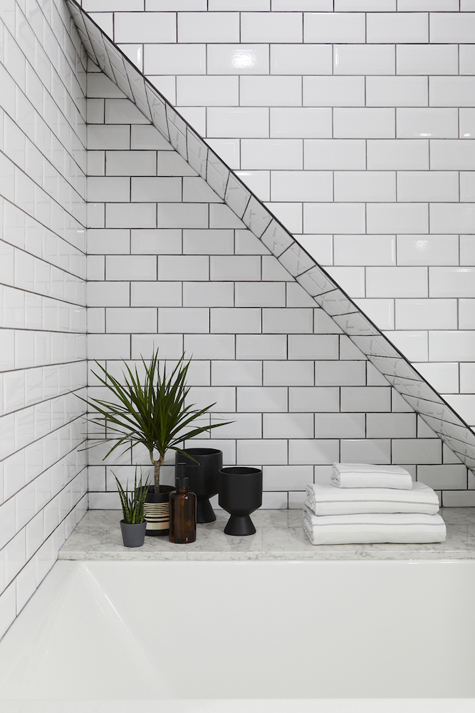 white subway tiles in bathroom with soaker tub and green plants and shelf