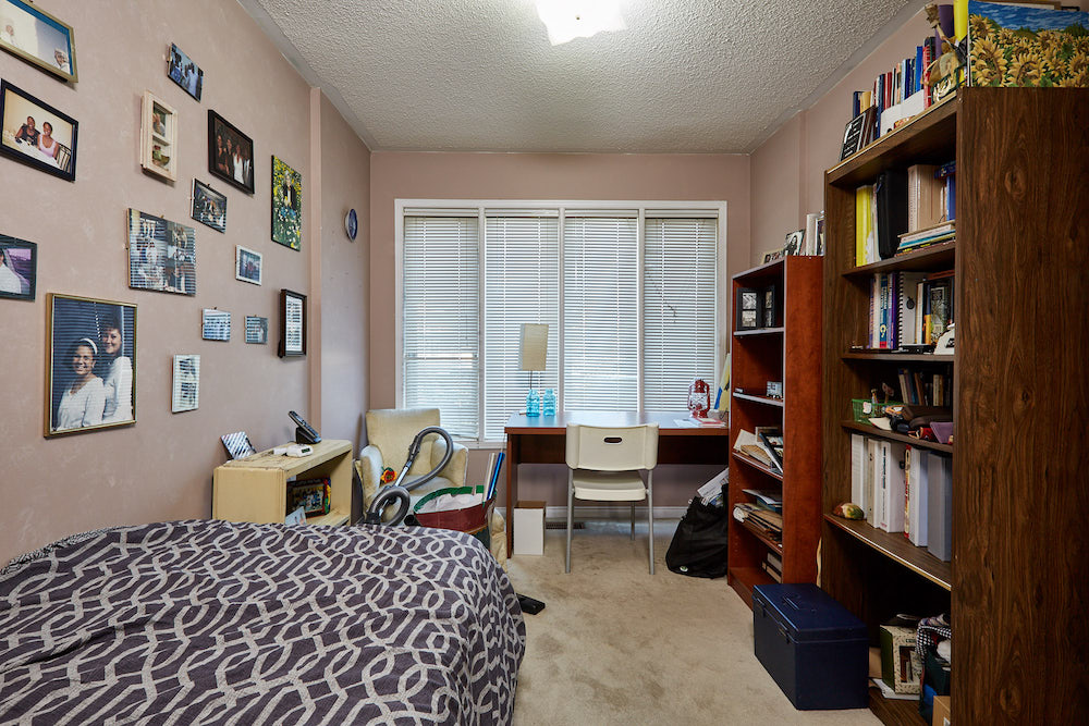 brown spare bedroom with bookshelves, a purple bed and photos on the wall