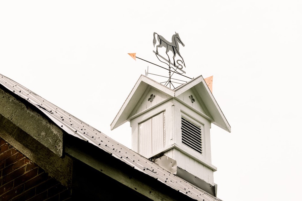white cupola with horse-themed weathervane on roof