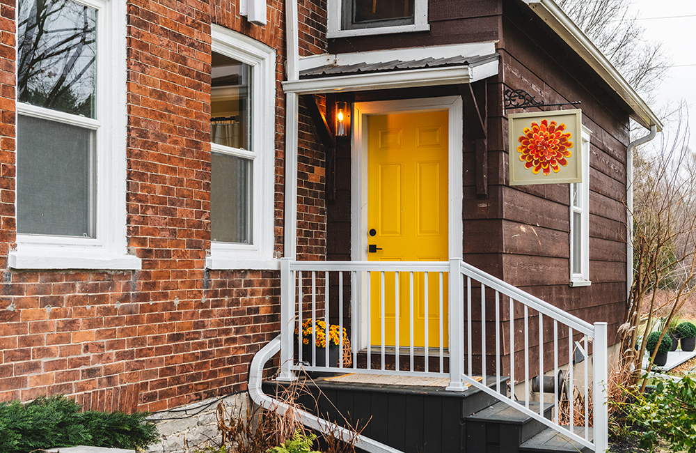 A bright yellow door on a red brick house.