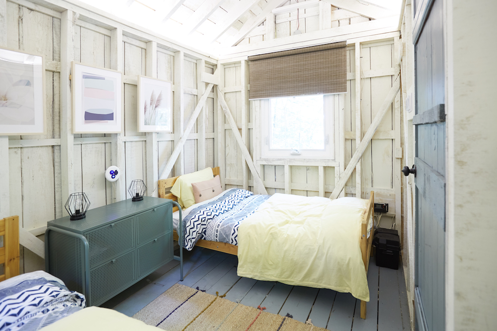 white interior of bunk house with twin beds and blue door