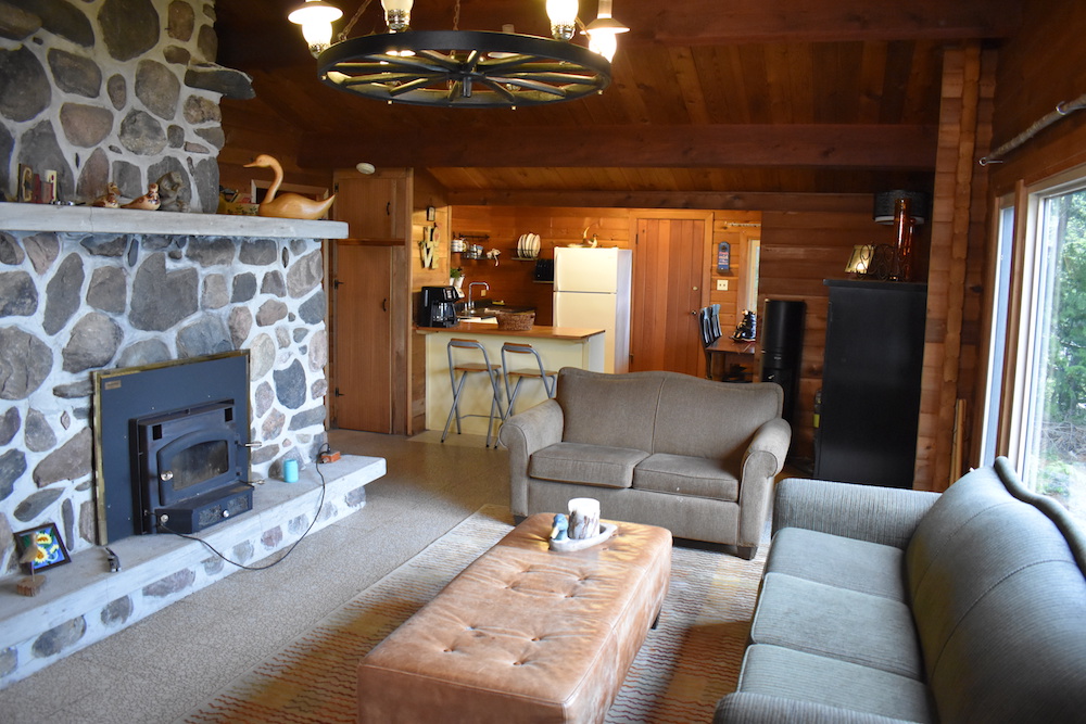 run down cottage interior with oversized fire place and grey couches