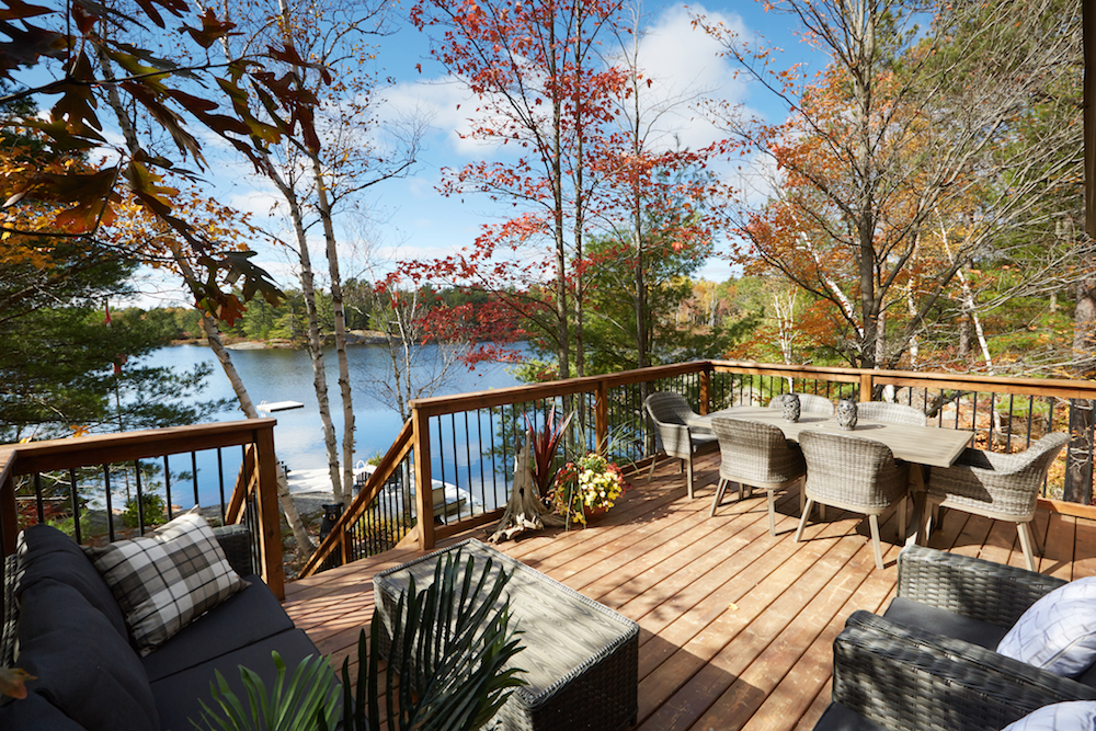wood deck with dining and lounge furniture in front of blue lake