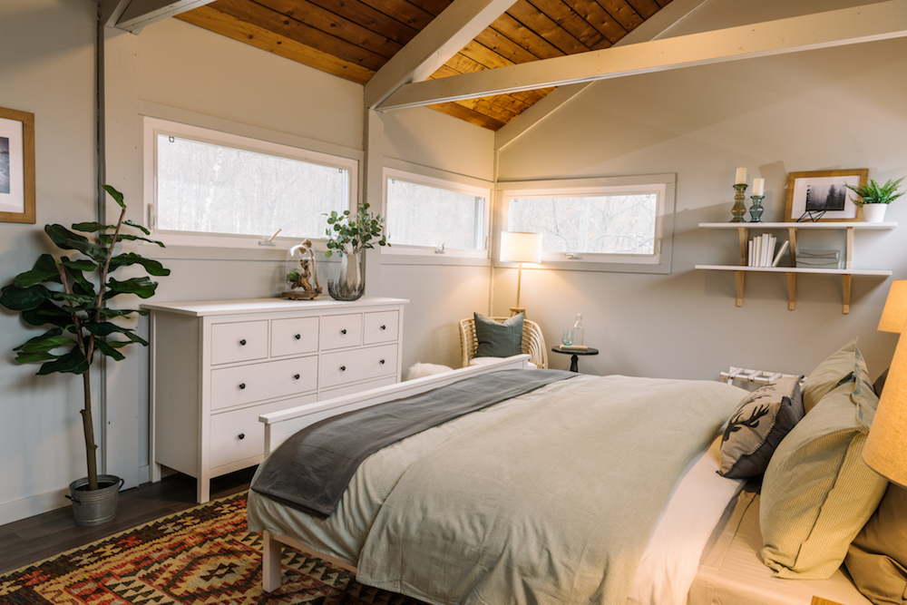 cozy white bedroom with wood ceiling and patterned rug