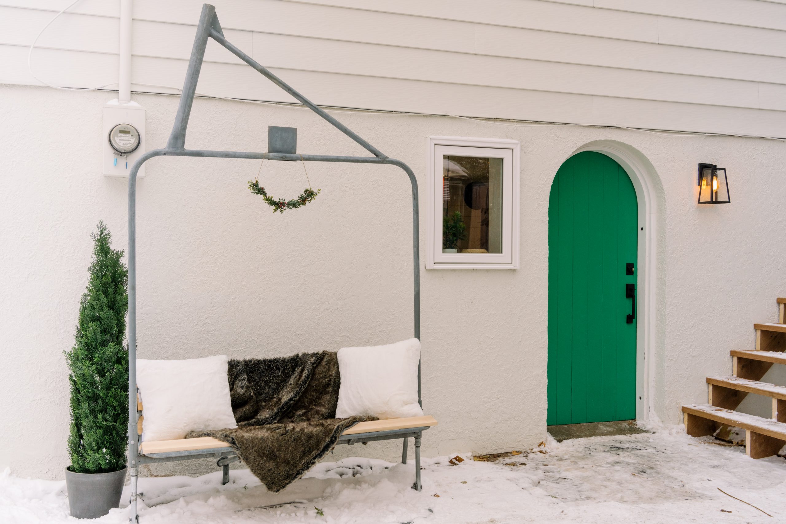 white house exterior with green door and chairlift bench