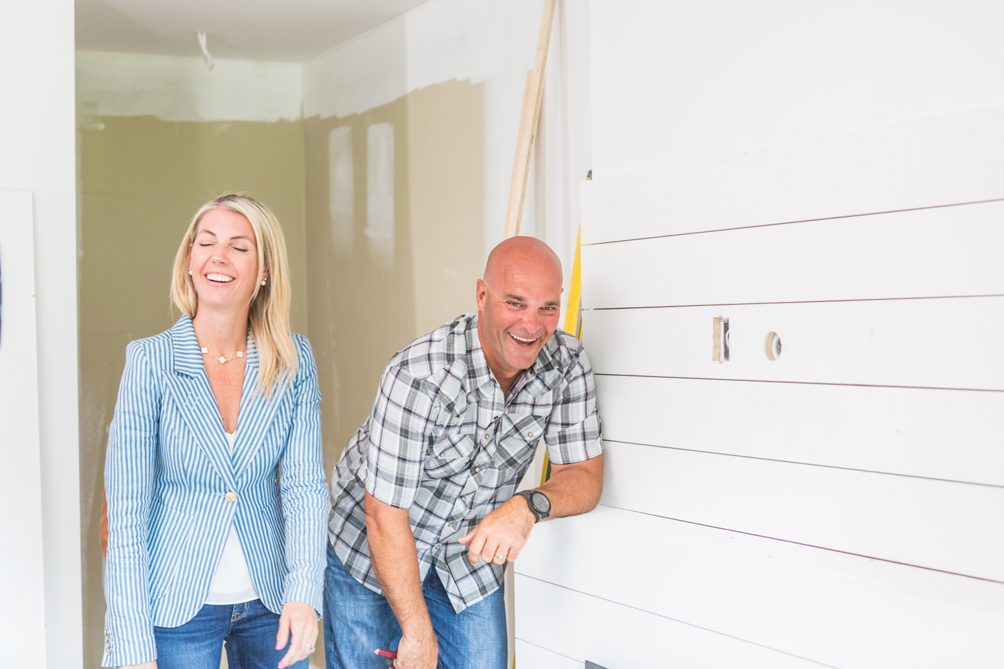 Bryan and Sarah Baeumler laughing in a room with neutral walls