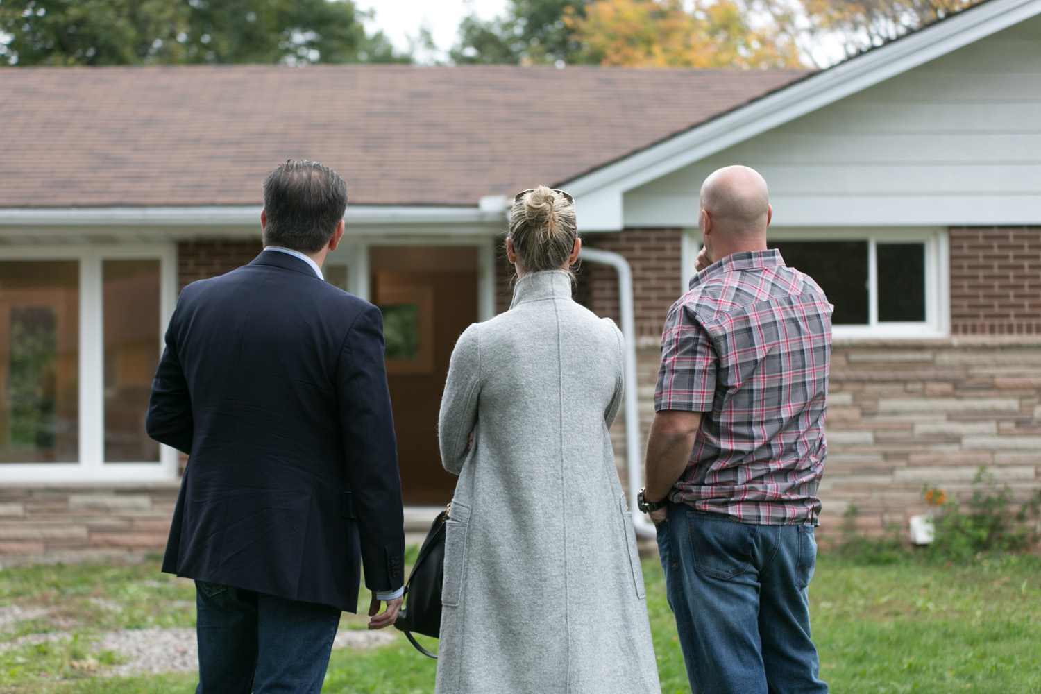 Sarah and Bryan Baeumler standing with an agent outside house
