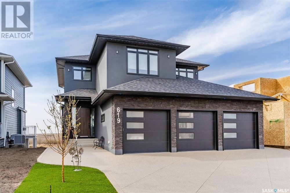 A modern three garage home painted black with a wooden front door