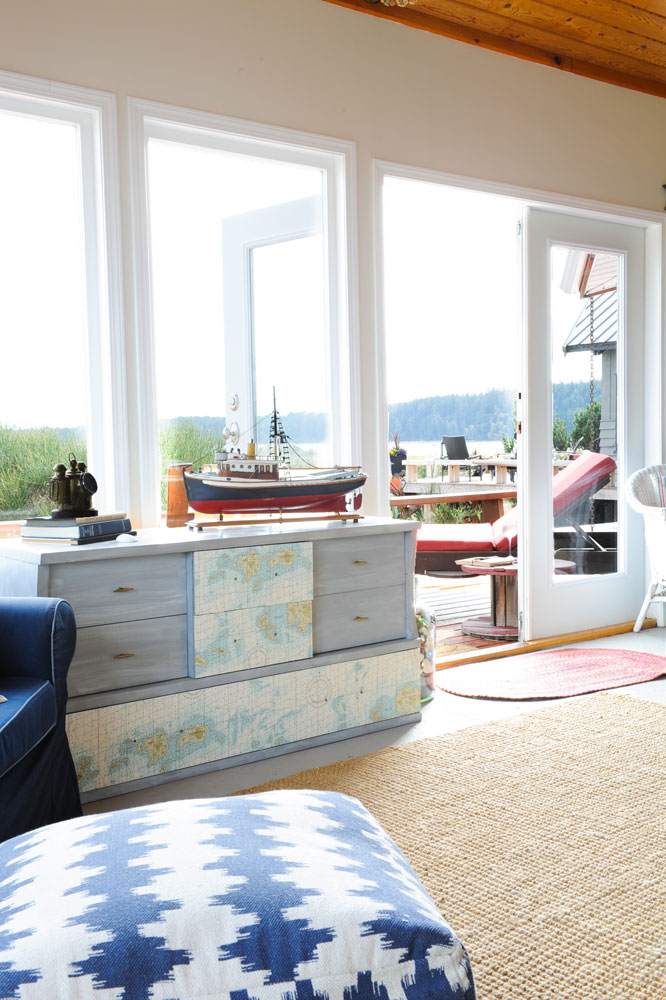 view to deck with blue and white ottoman in foreground and dresser with ship by window