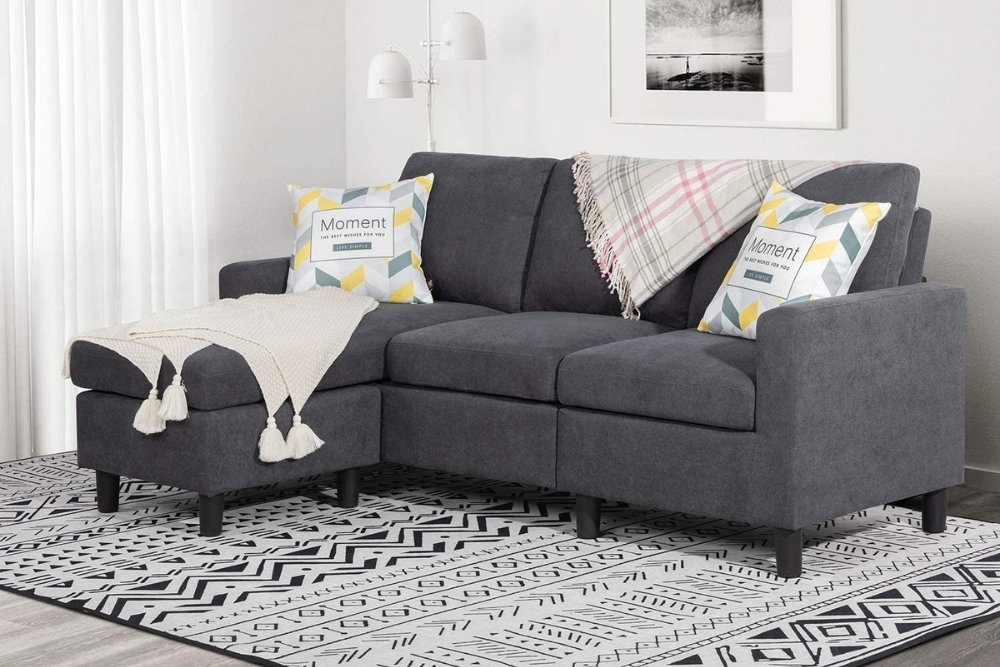 A small grey sectional on a black and white patterned rug.