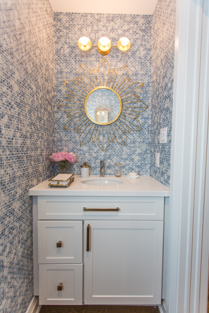 Main-floor powder room with gorgeous blue-patterned wallpaper and brass accents.