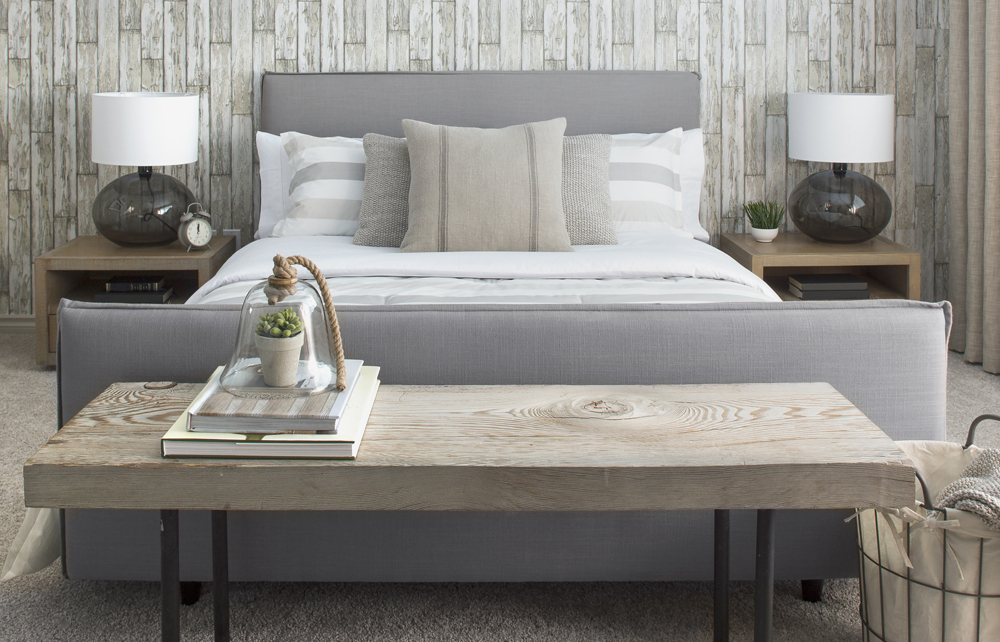 Bedroom in neutral tones with wood table at the end of the bed