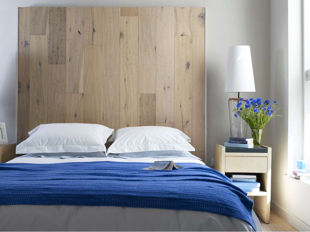 Neatly-organized bedroom with bright blue blanket and flowers on the night stand