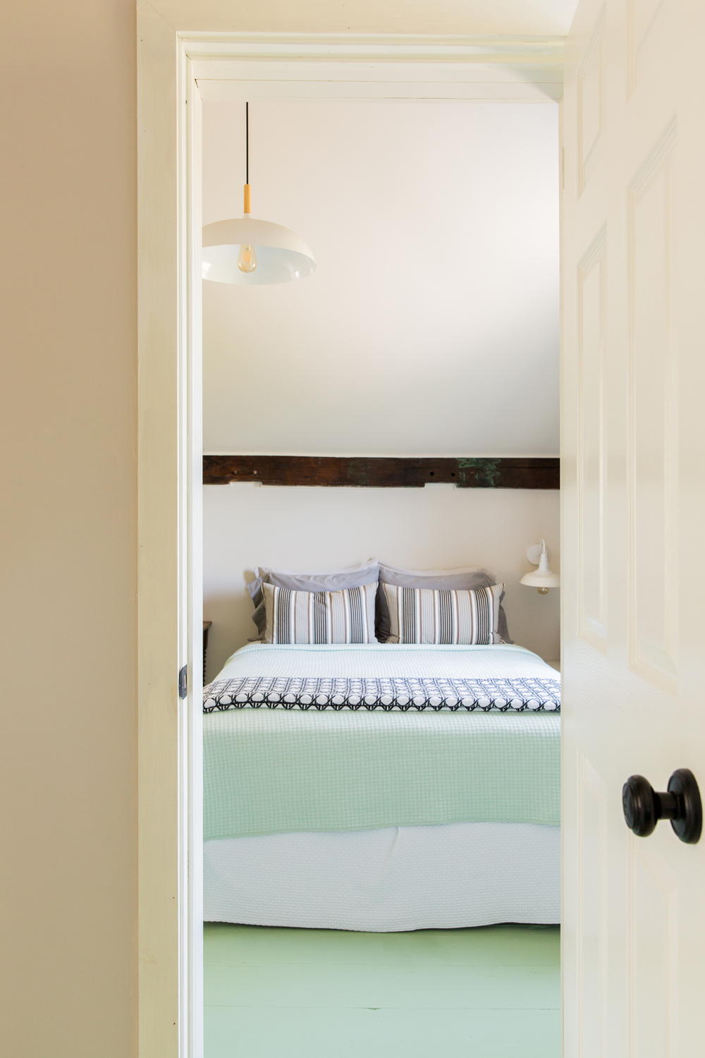 Bedroom with mint green bedding matching mint green hardwood floors