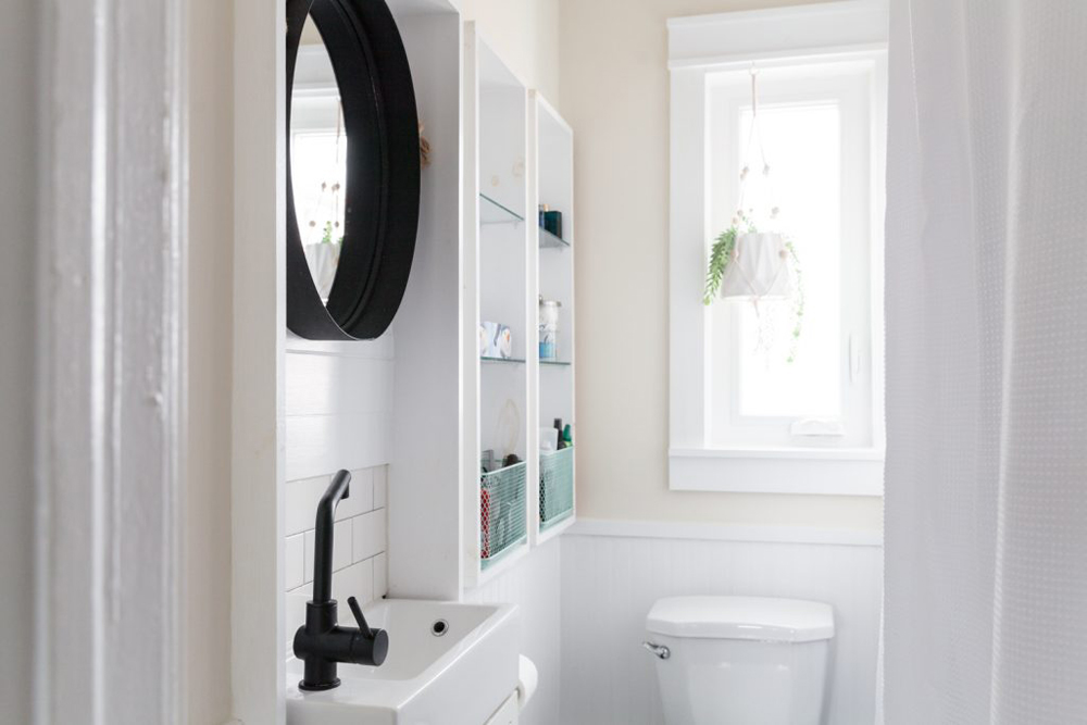 White bathroom with black accents and vertical shelving