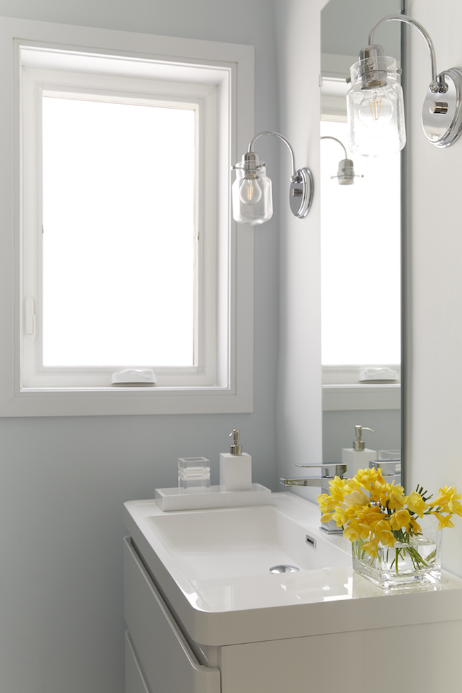 White bathroom with large window and overhead lighting
