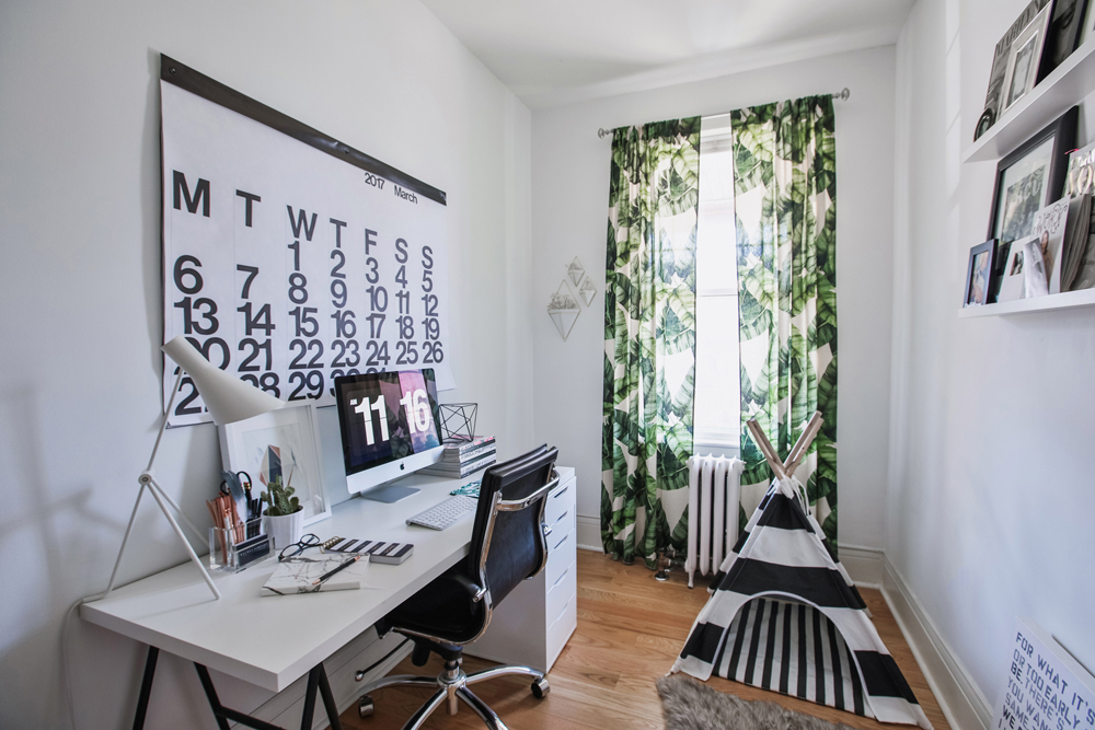 Small home office with white desk and graphic nature curtain