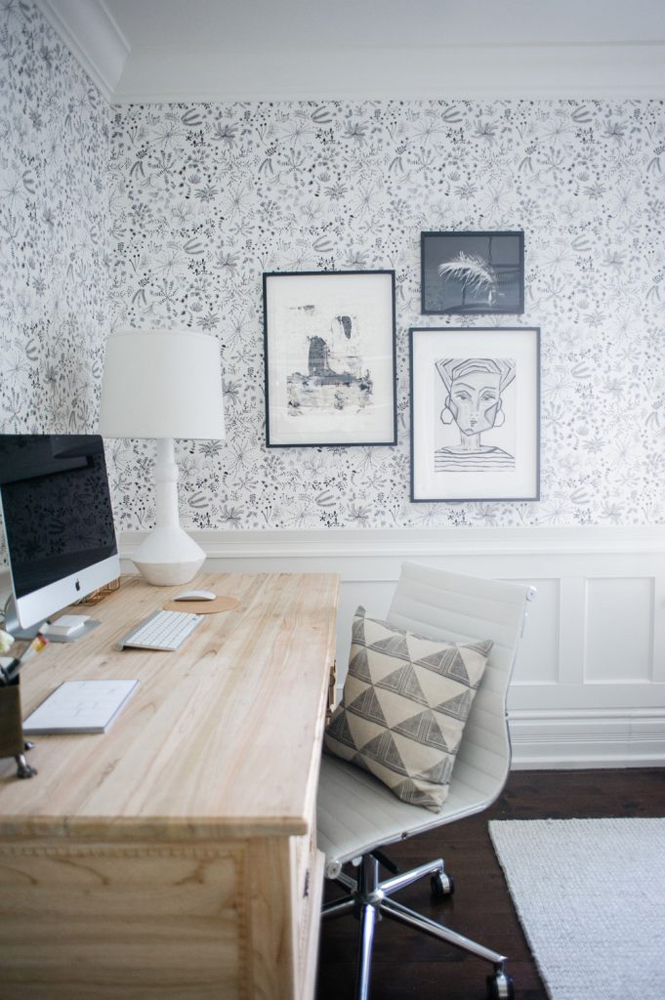 Home office with wood desk, graphic wallpaper and artwork