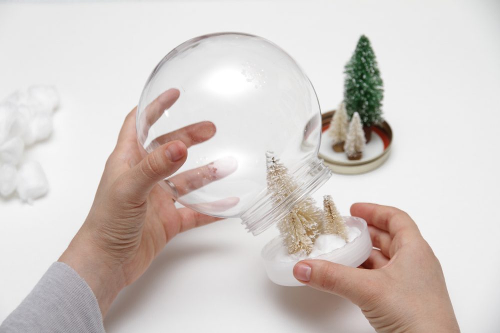 Twisting lid onto glass globe of snow globe