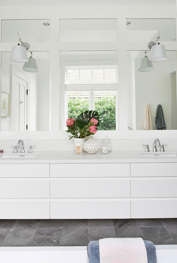 white bathroom vanity with double sinkd, panelled mirrors and white sconces on mirrors