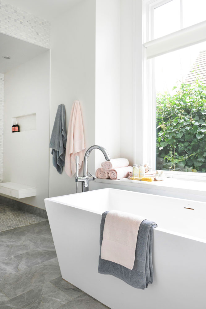 white angular tub by window with grey and pink towels