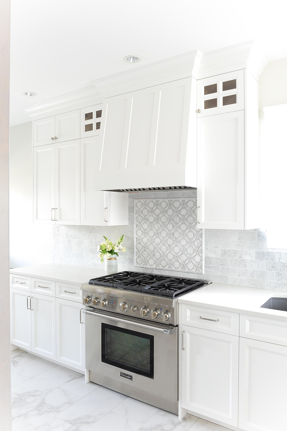 Modern white kitchen with custom subtle range hood.