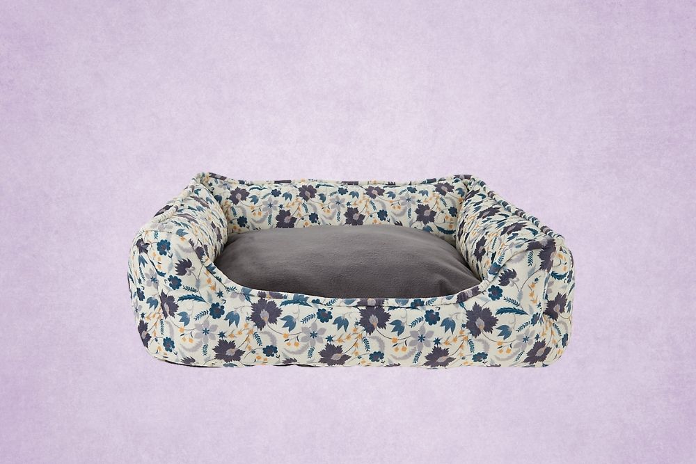 A navy and gray floral dog bed on a purple background