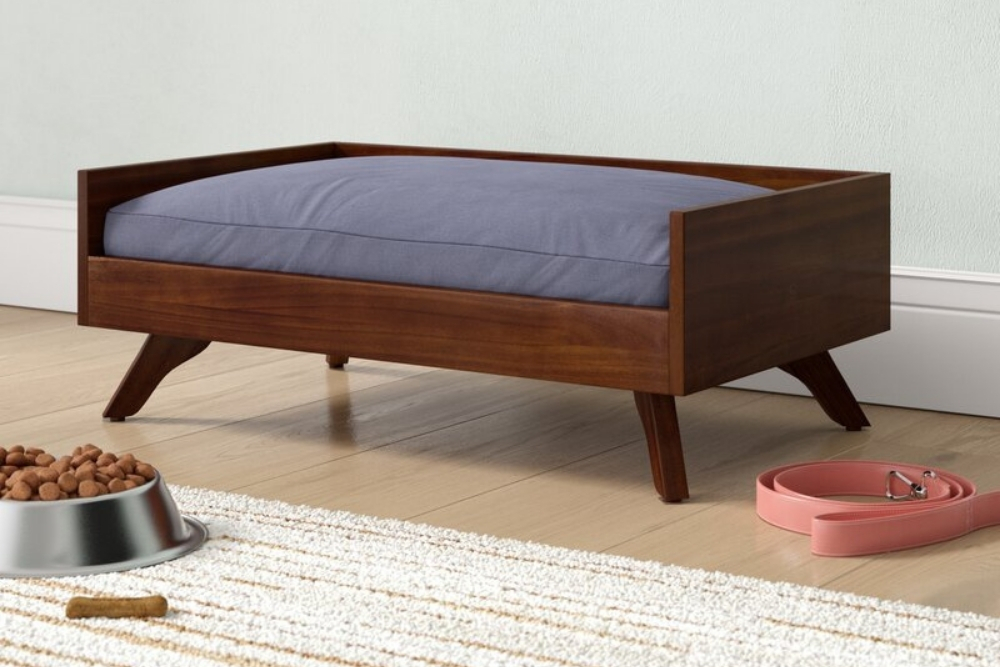 A wooden midcentury dog bed with a blue cushion