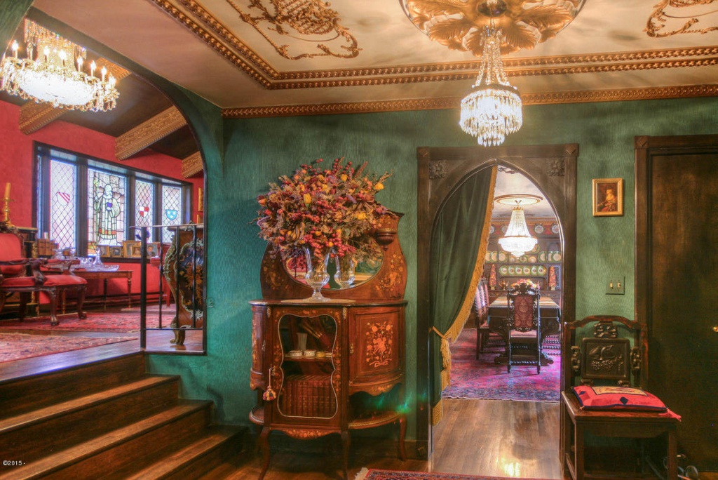 A Renaissance-themed house interior, complete with dark green walls, plush furniture and elaborate chandeliers