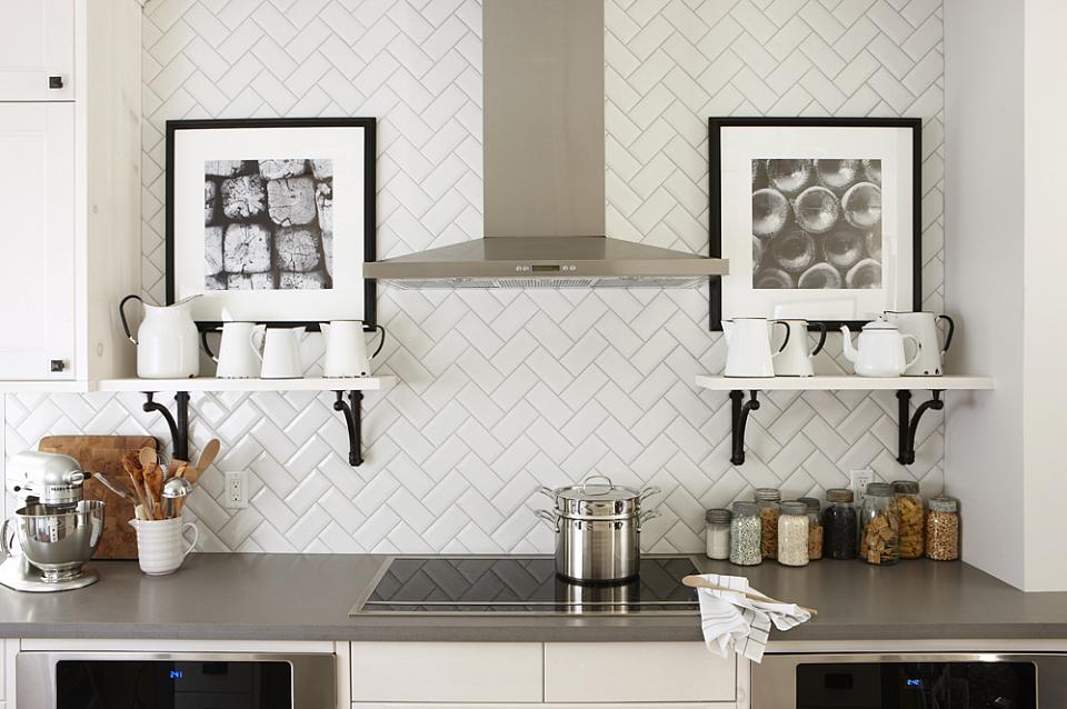Modern kitchen with herringbone subway tile and white open shelves with black hinges.