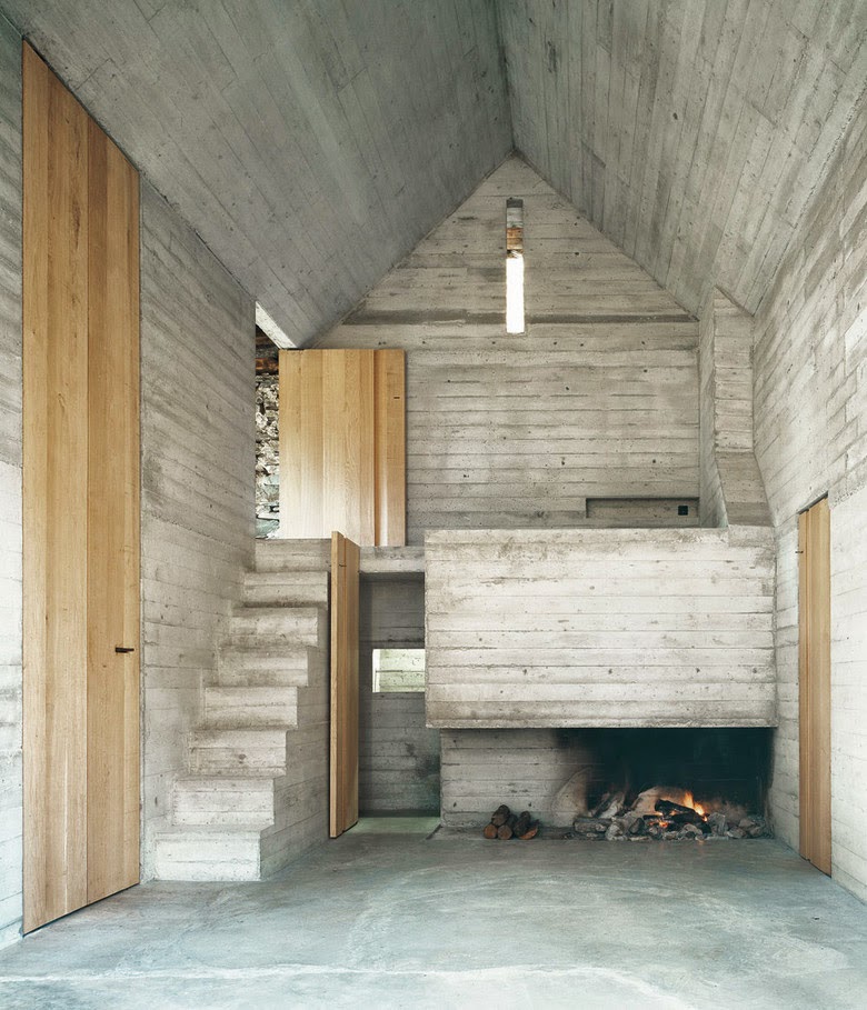 Concrete interior with old rustic fireplace beneath entrance stairs