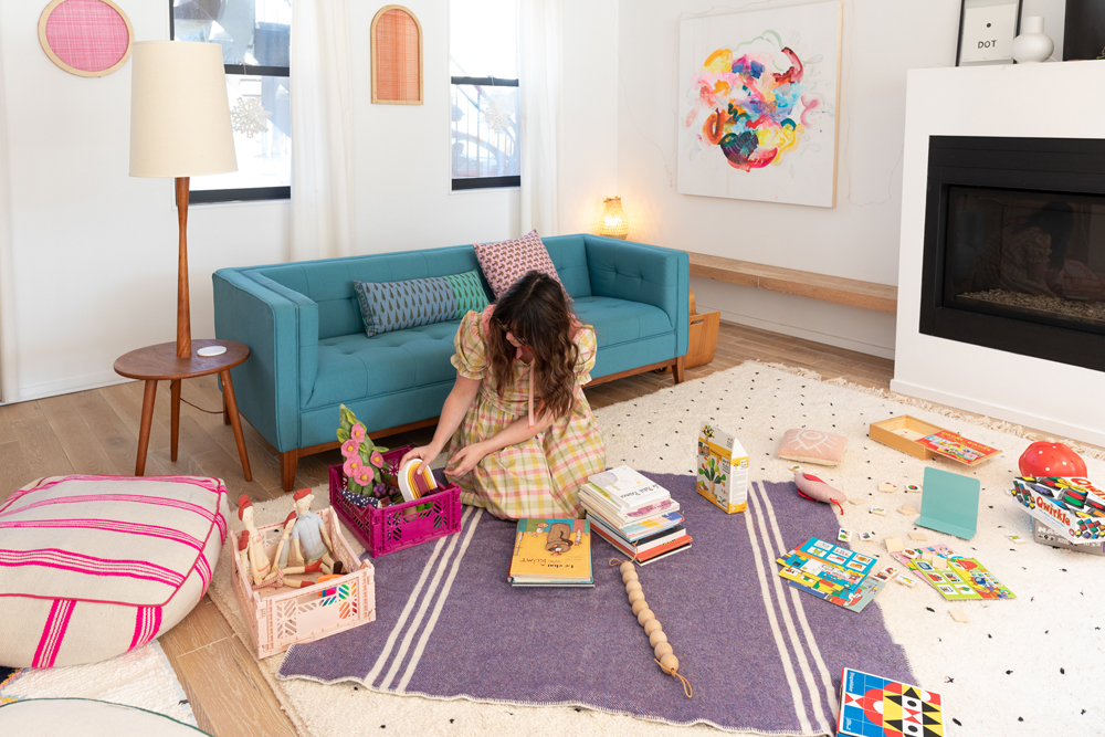 Maca organizing toys and books in living room