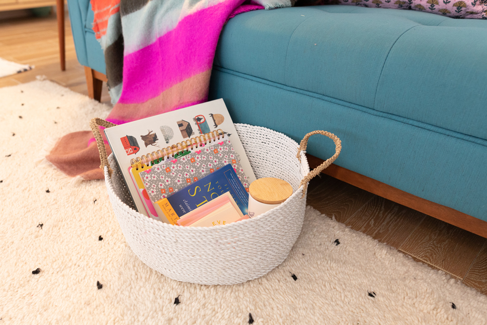 white basket filled with self-care items beside blue couch