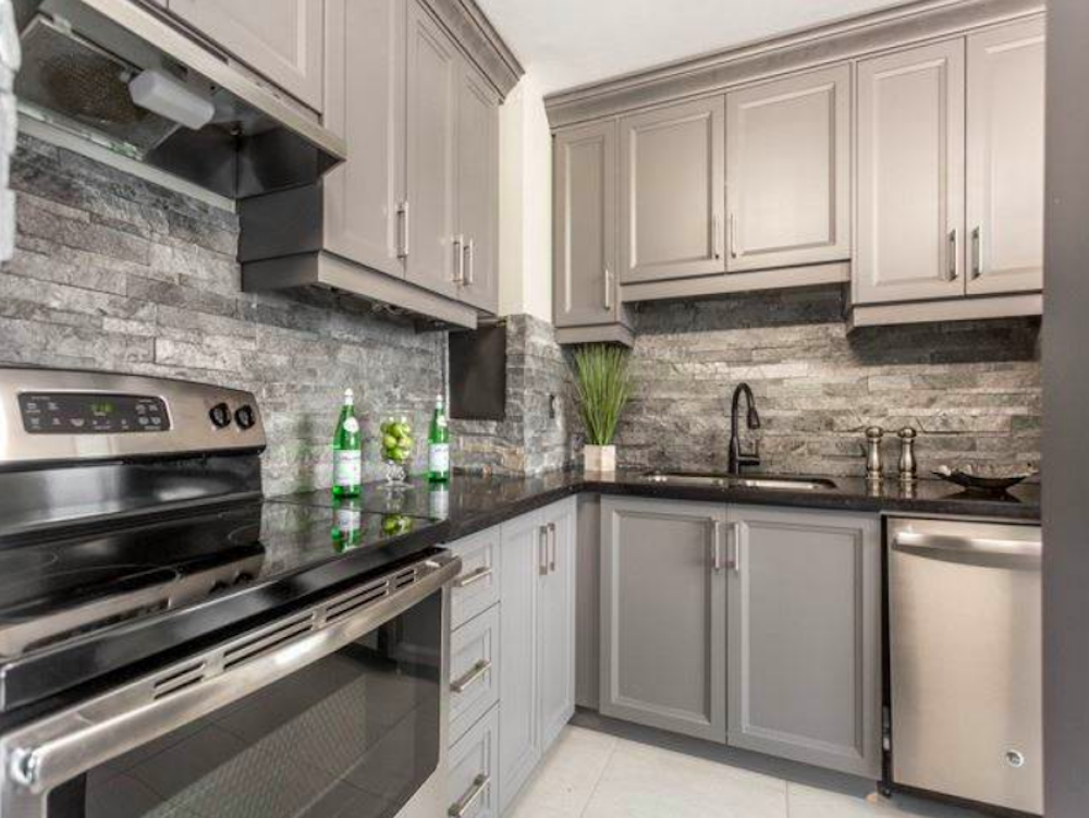 Kitchen with stone backsplash and grey cabinets