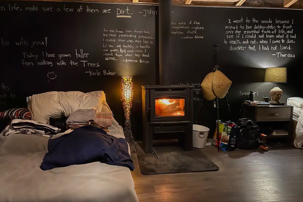 Cottage interior with beds, wood stove and chalkboard wall