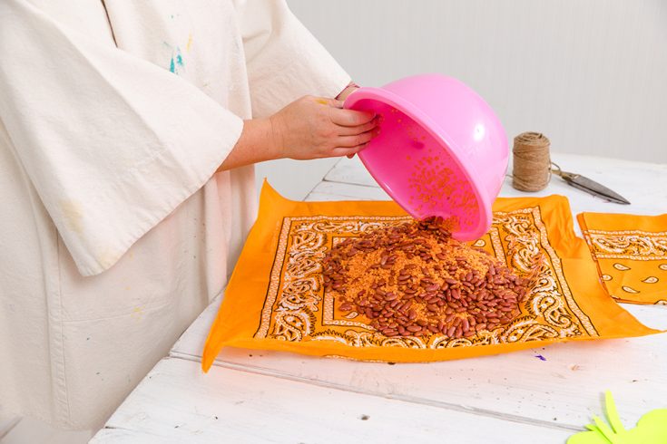 Tiffany Pratt pouring beans and rice onto an orange bandana