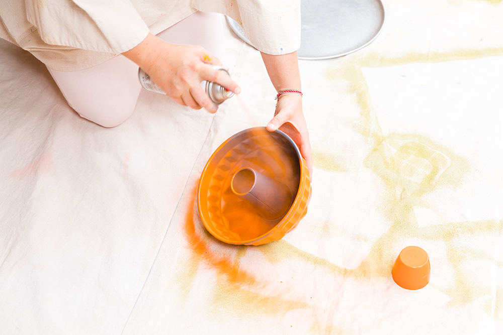 Tiffany Pratt spraying a bundt pan with orange paint