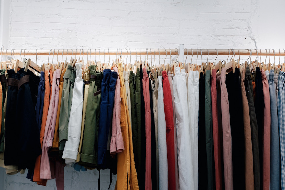 colourful clothes hanging on rail against a white wall