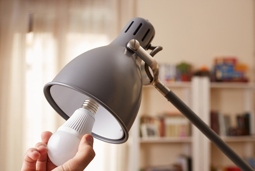 A hand inserting a new lightbulb in a lamp