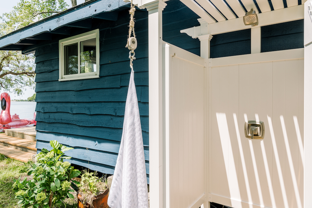 white outdoor shower beside blue cottage