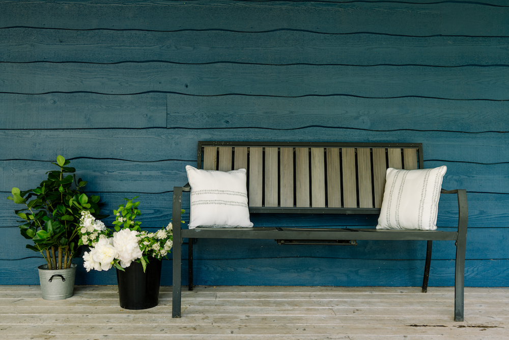 blue cottage exterior with bench and potted palnts
