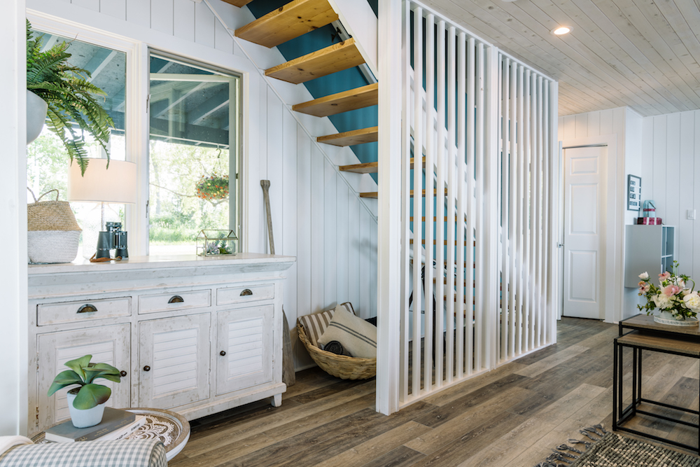 beach-themed white living room with wooden staircase and nautical antiques